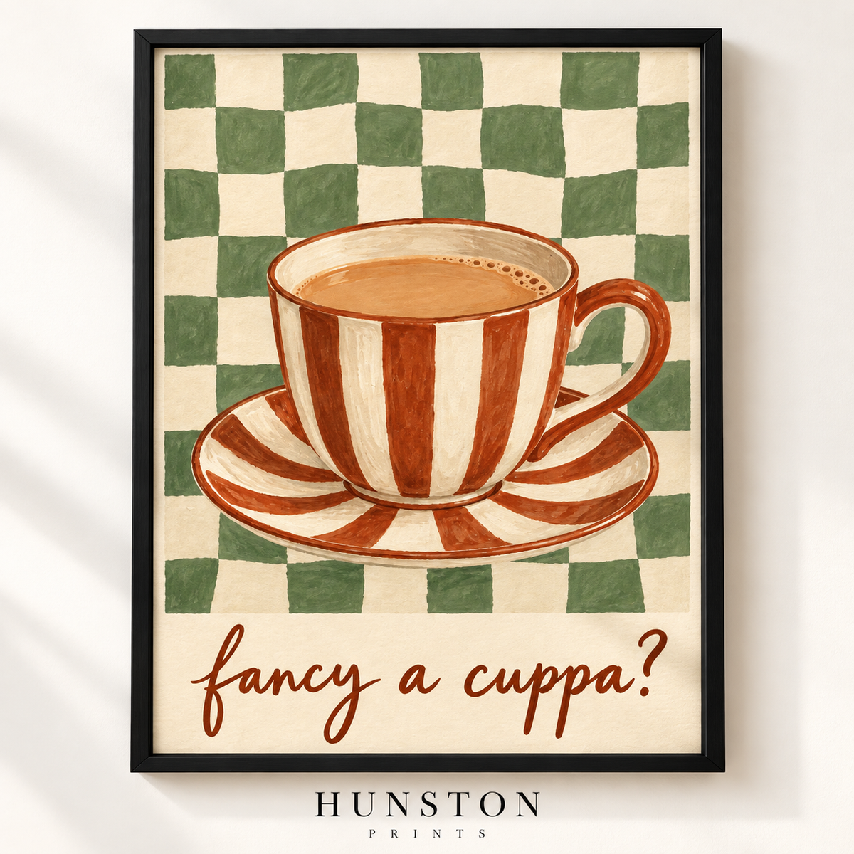 Red striped teacup of tea on a green checkerboard background with the words fancy a cuppa