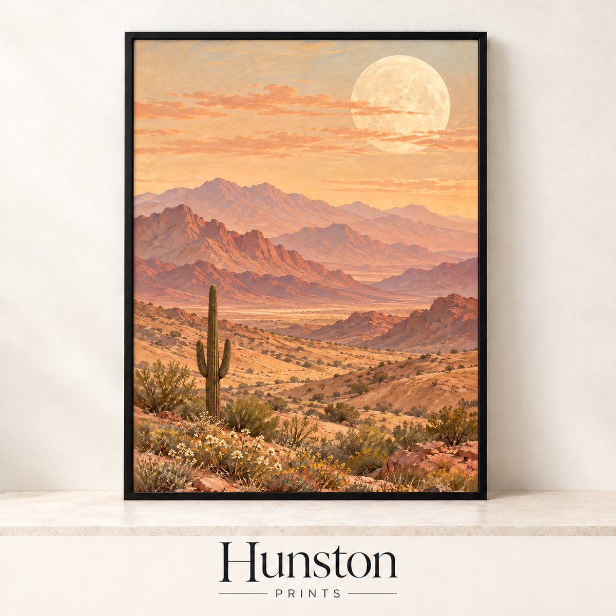 Saguaro cactus with a full moon rising over pink desert mountains