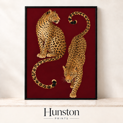 Two leopards with curling tails on a deep burgundy background