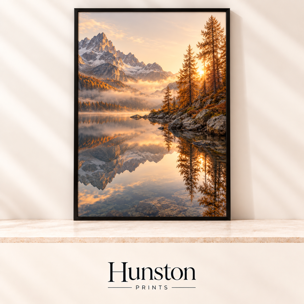 Snowy mountains reflected in a still alpine lake at sunrise with golden larch trees