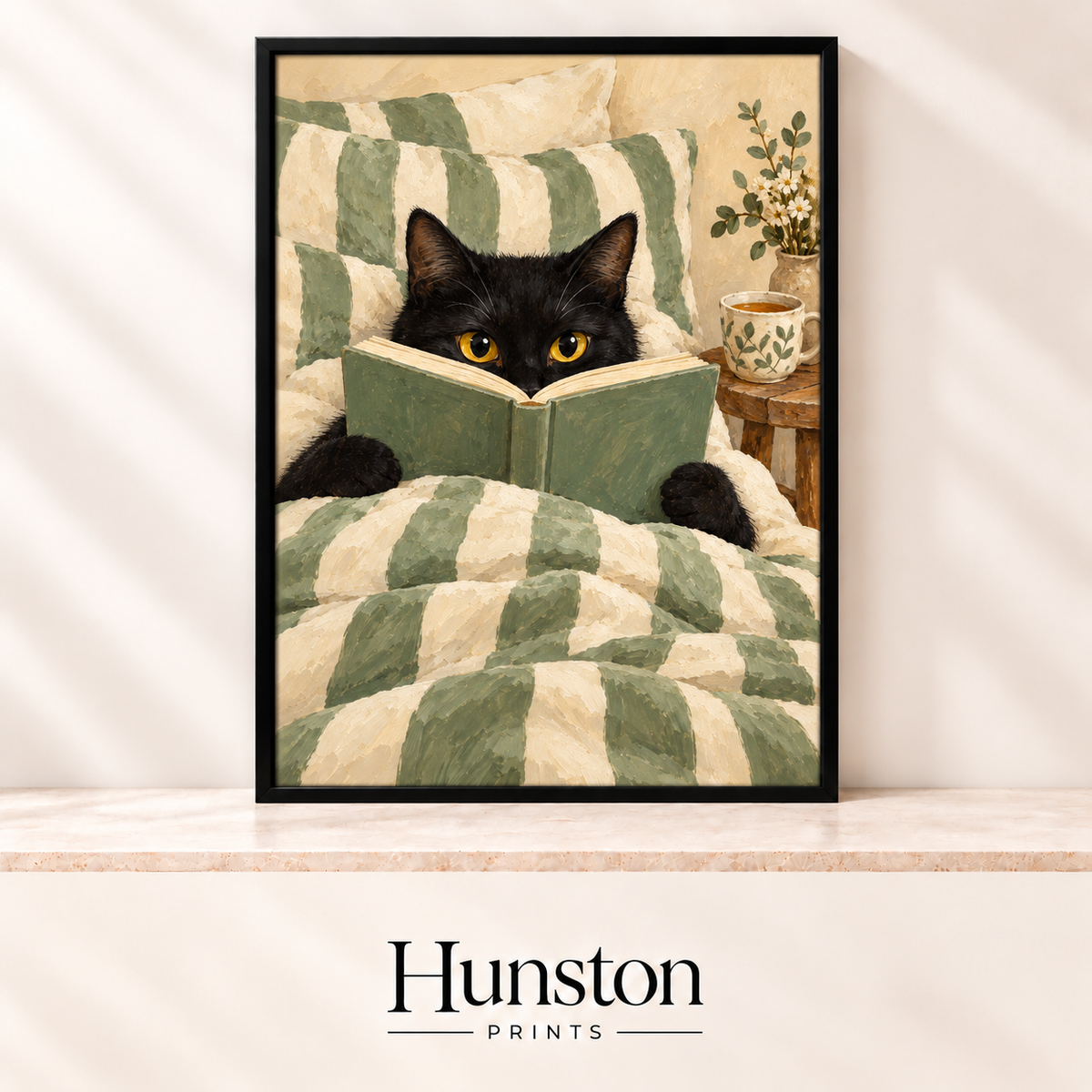 Black cat peeking over a book in bed with sage green striped bedding and a cup of tea