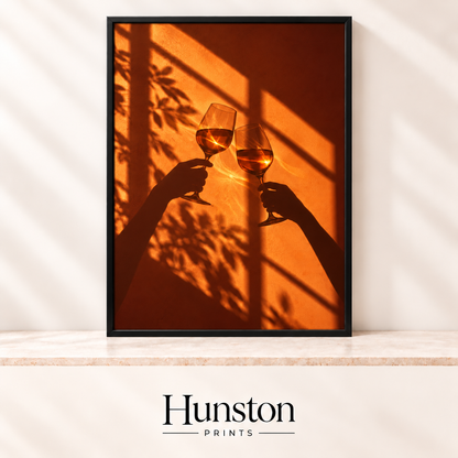 Silhouetted hands toasting wine glasses against an orange wall with window and leaf shadows