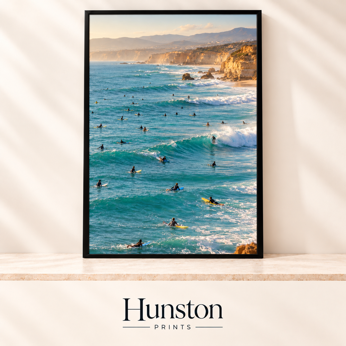 Surfers riding turquoise waves beneath golden coastal cliffs at sunset
