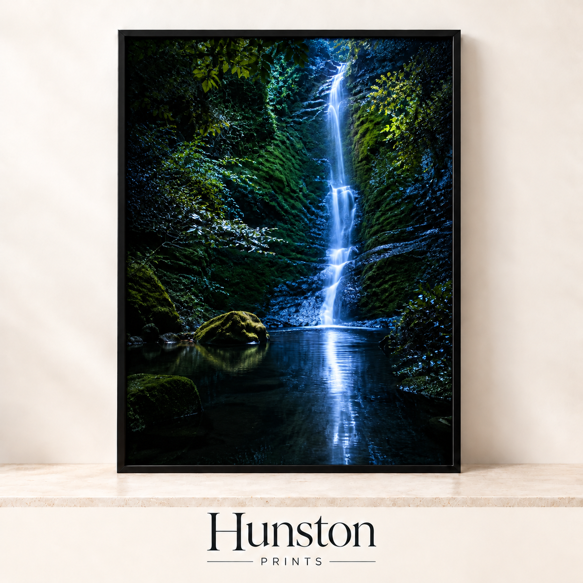 Slender waterfall falling into a dark pool in a mossy gorge