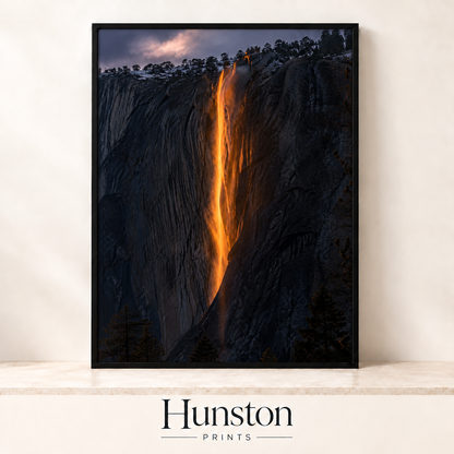 Waterfall glowing orange like fire down a dark granite cliff