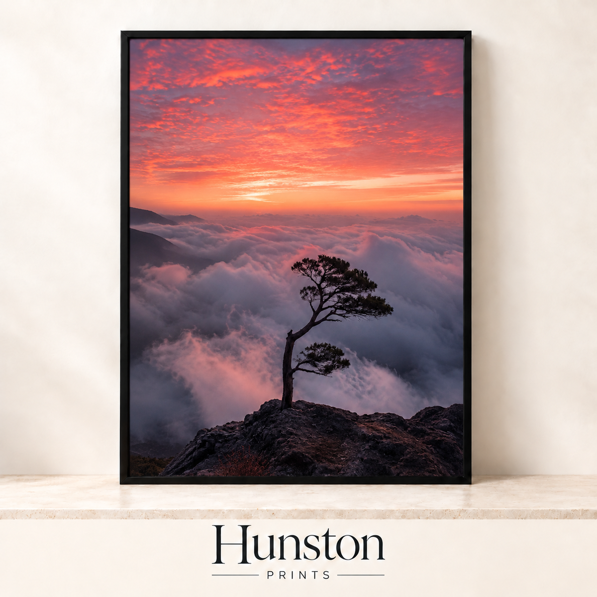 Lone pine tree on a rocky peak above clouds at sunrise