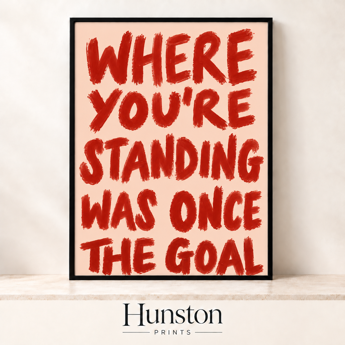 Red brush lettering reading Where you're standing was once the goal on pink