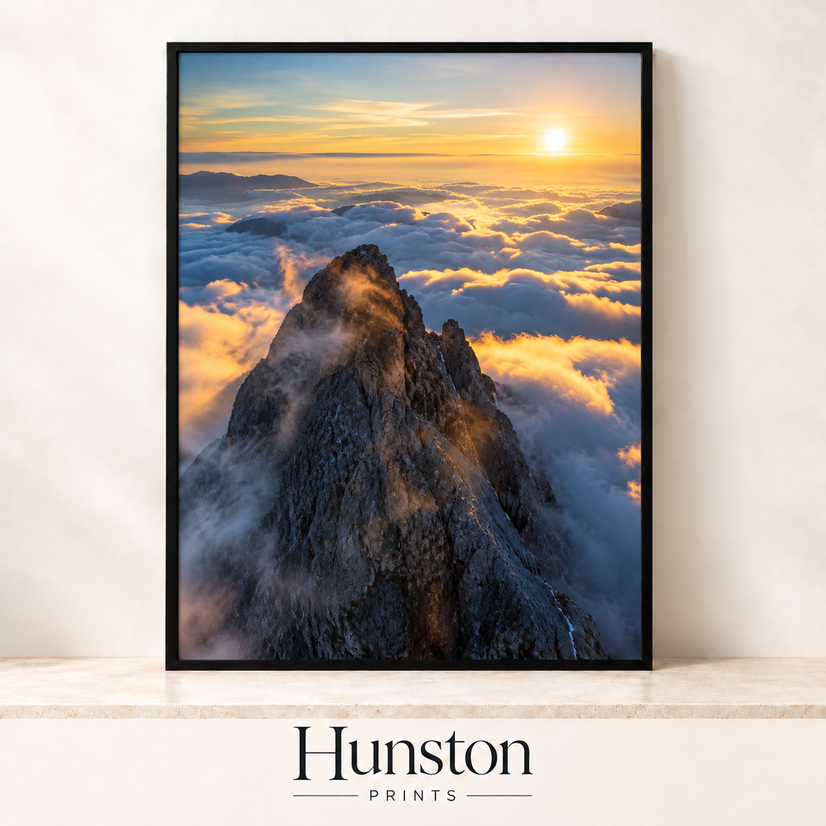 Jagged mountain peak rising above golden clouds at sunset