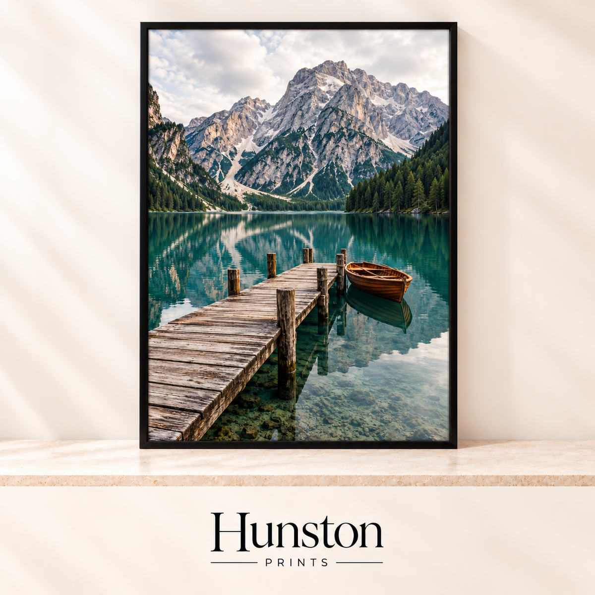 Wooden jetty and rowing boat on a clear emerald mountain lake below rocky peaks